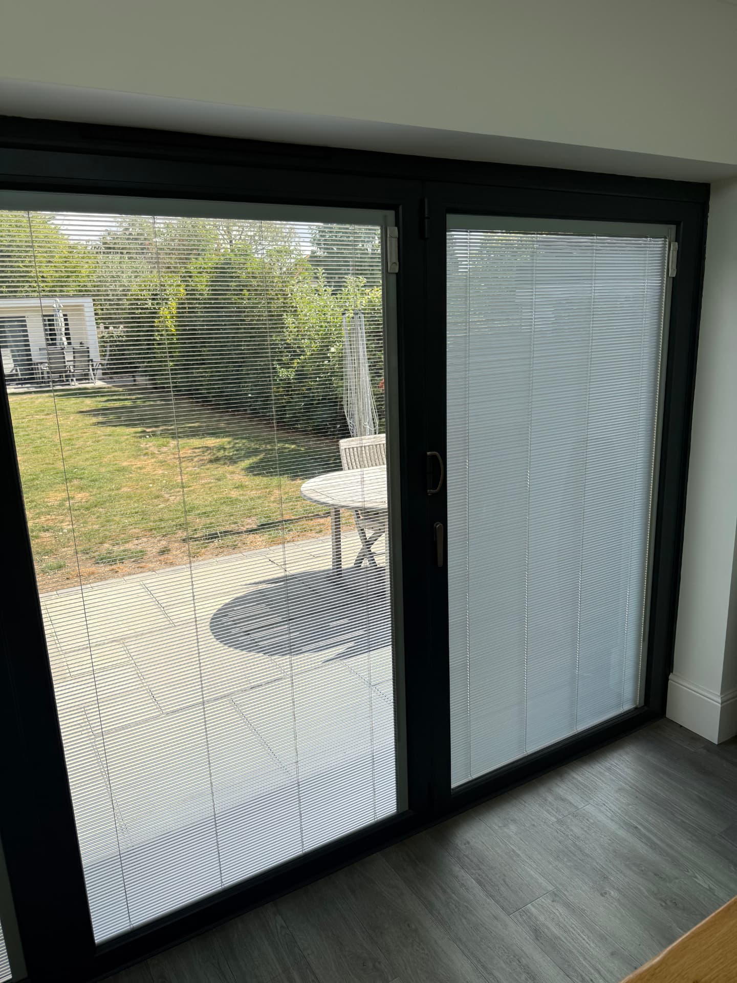 Integral blinds fitted to bi-fold doors, one leaf with slats open and one closed for privacy